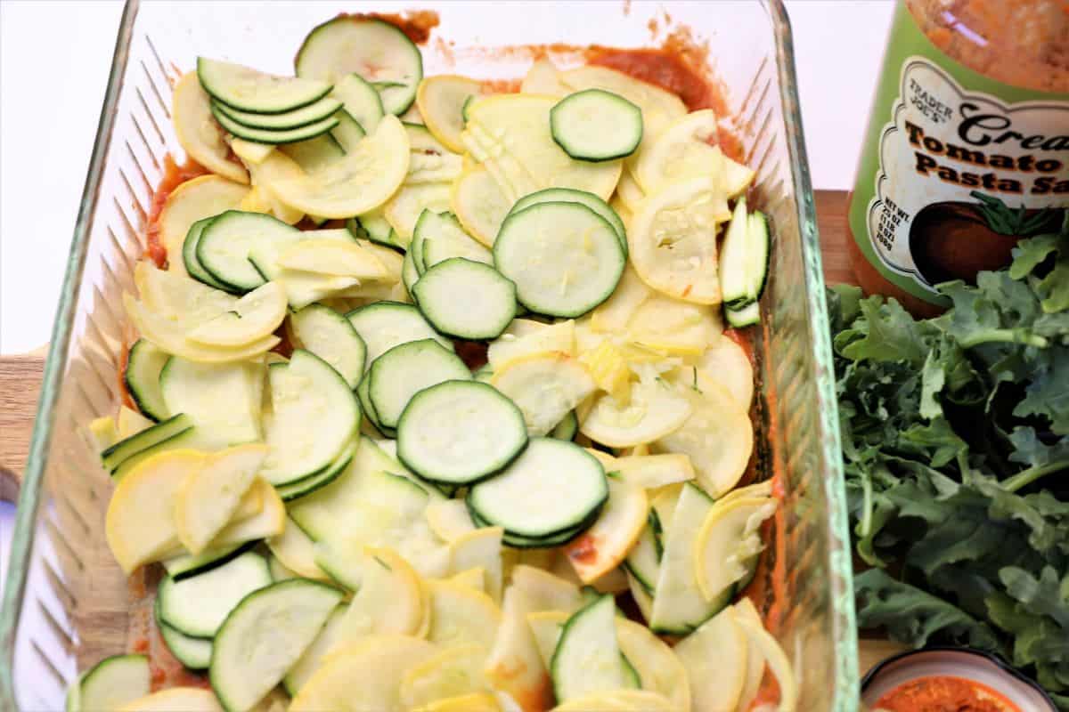 zucchini and yellow squash being layered in baking dish