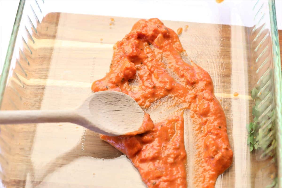 spreading pasta sauce in baking dish