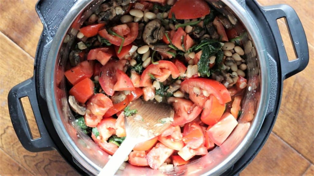 tomatoes are added to the instant pot with the sauteed vegetables 