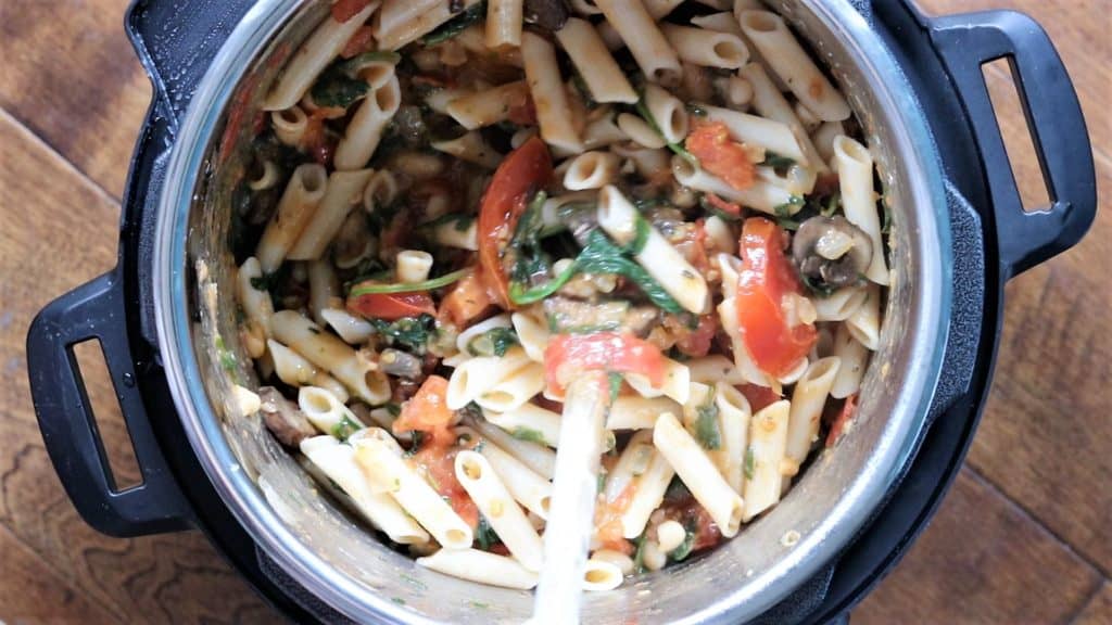 mixing the pasta and sautéed vegetables in the instant pot