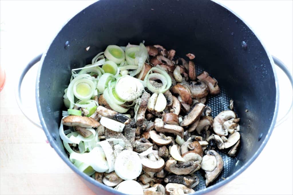 sliced mushrooms, leeks, and garlic satueing in a large pot. 
