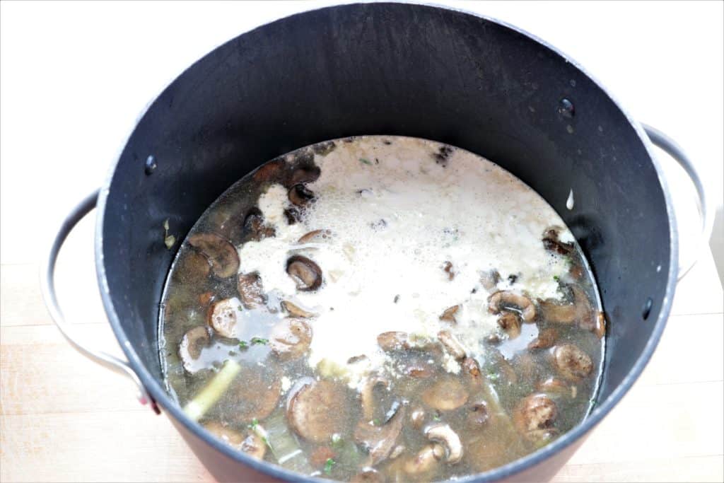 vegetable broth and garlic cashew cream sauce being added to large pot