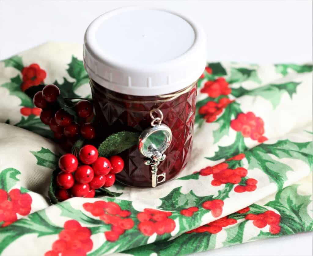 jar of blackberry jam on christmas napking with berries