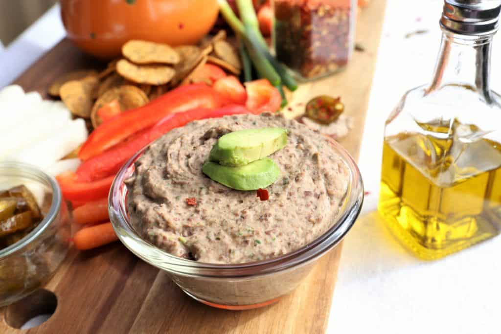 Black Bean Dip in a small glass bowl topped with fresh avocado