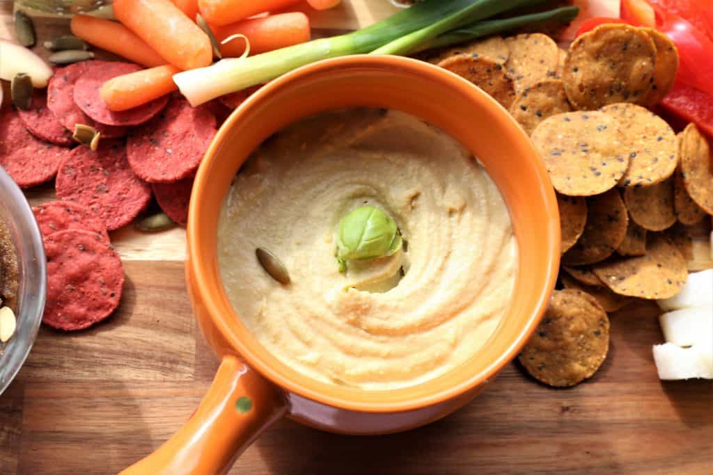 Basil Hummus Dip in a orange serving bowl for vegan dip and veggie platter