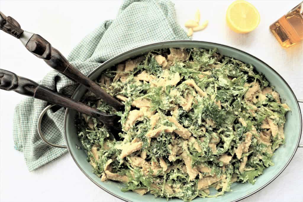Lentil pasta with kale in bowl with large spoons
