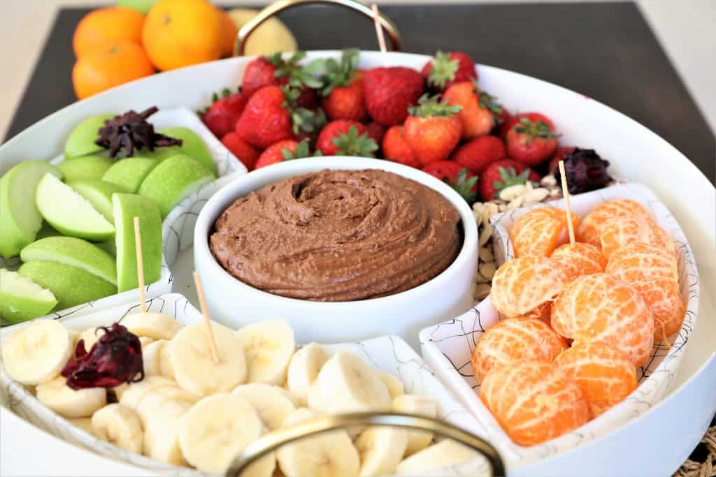 Chocolate Hummus in a serving platter with apples, strawberries, bananas, and mandarin oranges.