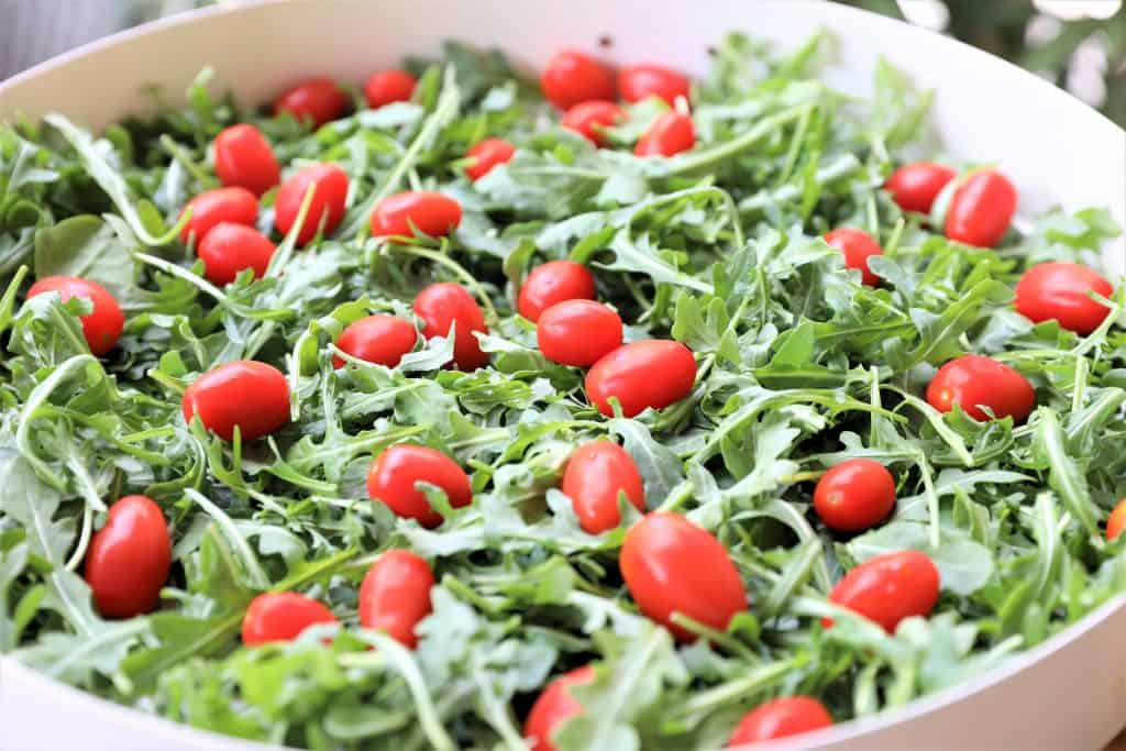 Add tomatoes and agugula to salad bowl