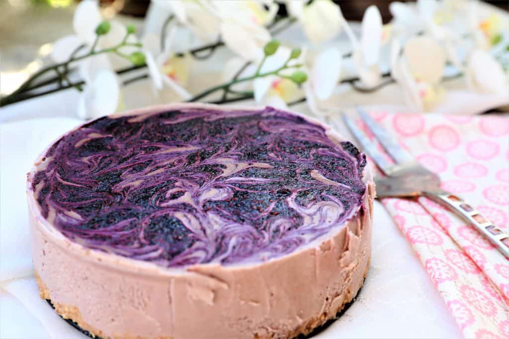 vegan berry cheesecake with flowers in the background
