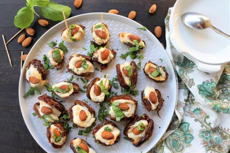 creamy stuffed dates on a white plate with a napkin next to them