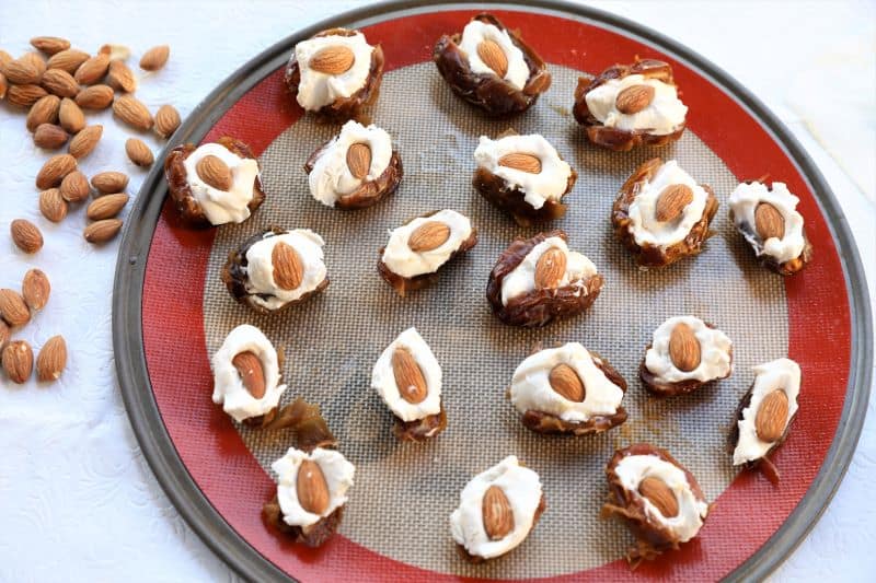 dates stuffed with cream cheese and almond on a baking pan
