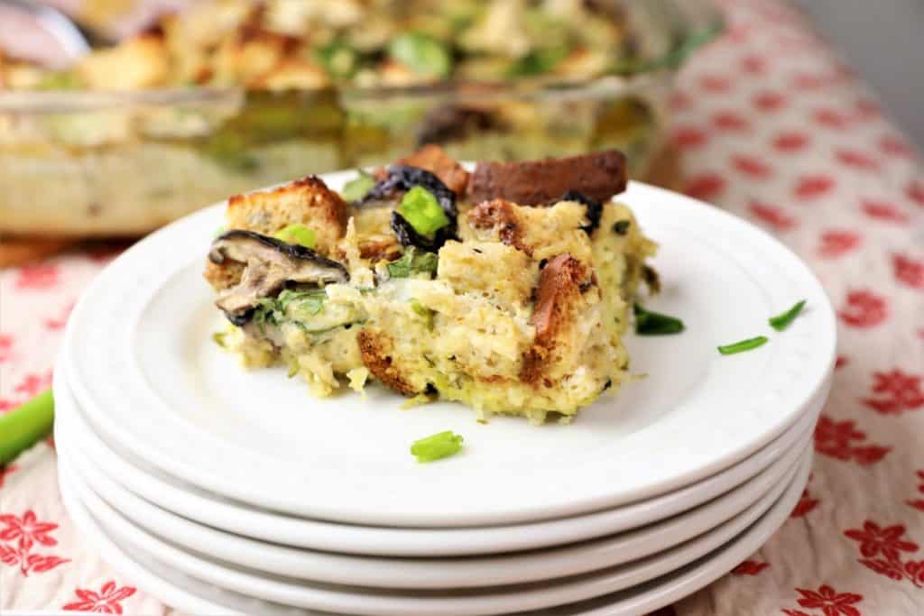Serving of Spinach, potato mushroom breakfast casserole on a stack of white plates