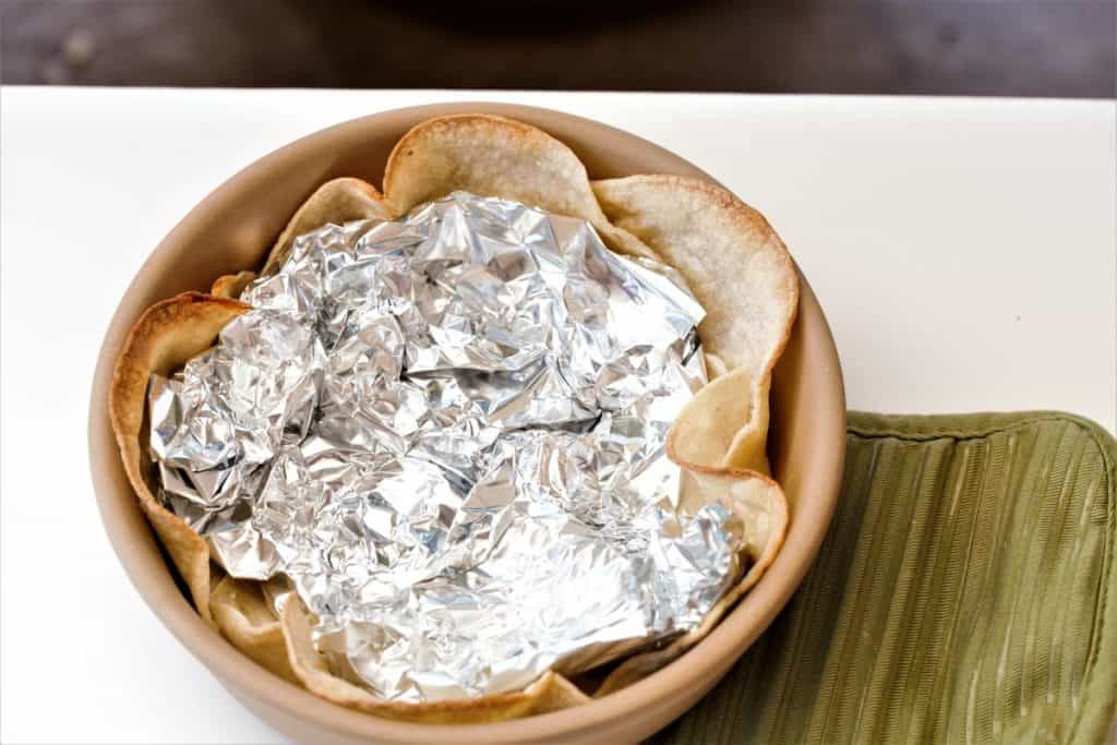 Place corn tortillas in bowl and set with tinfoil. Bake.