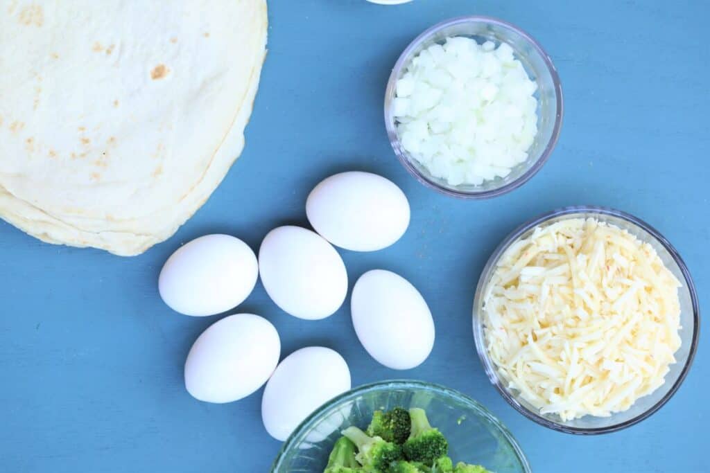 Ingredients for broccoli casserole--eggs, tortillas, onion, broccoli, cheese
